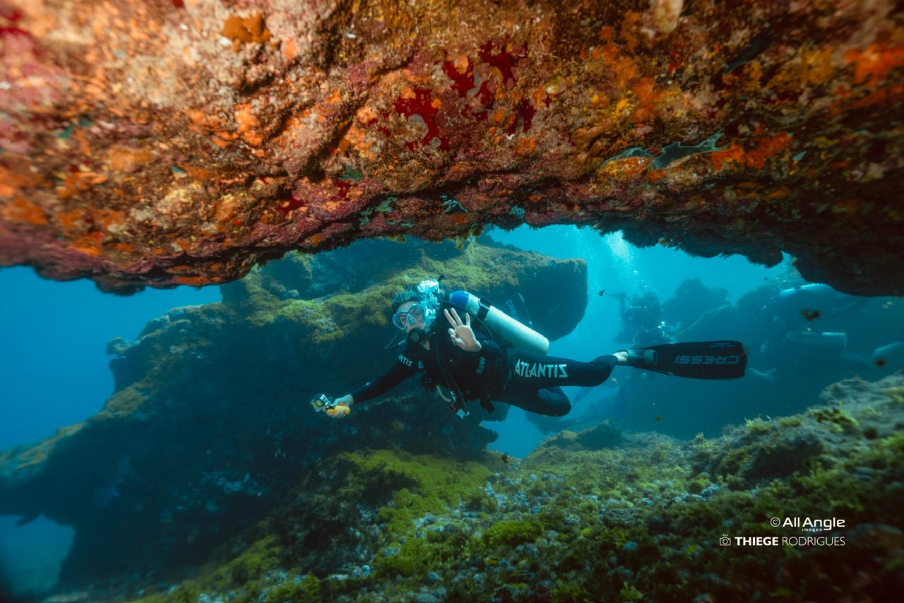 Mergulhadora passando sob uma formação rochosa submersa