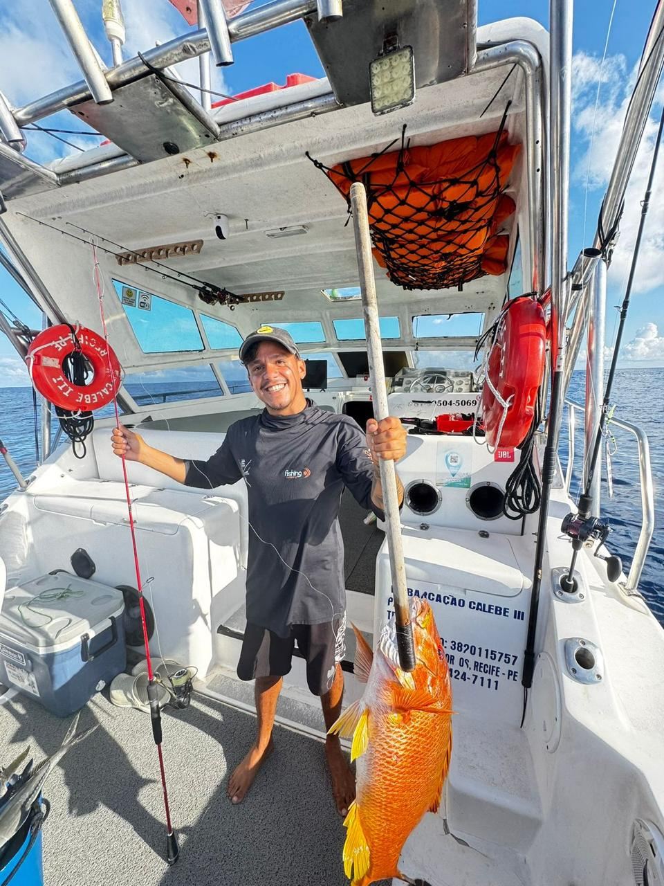 Pescador com peixe laranja capturado em Fernando de Noronha