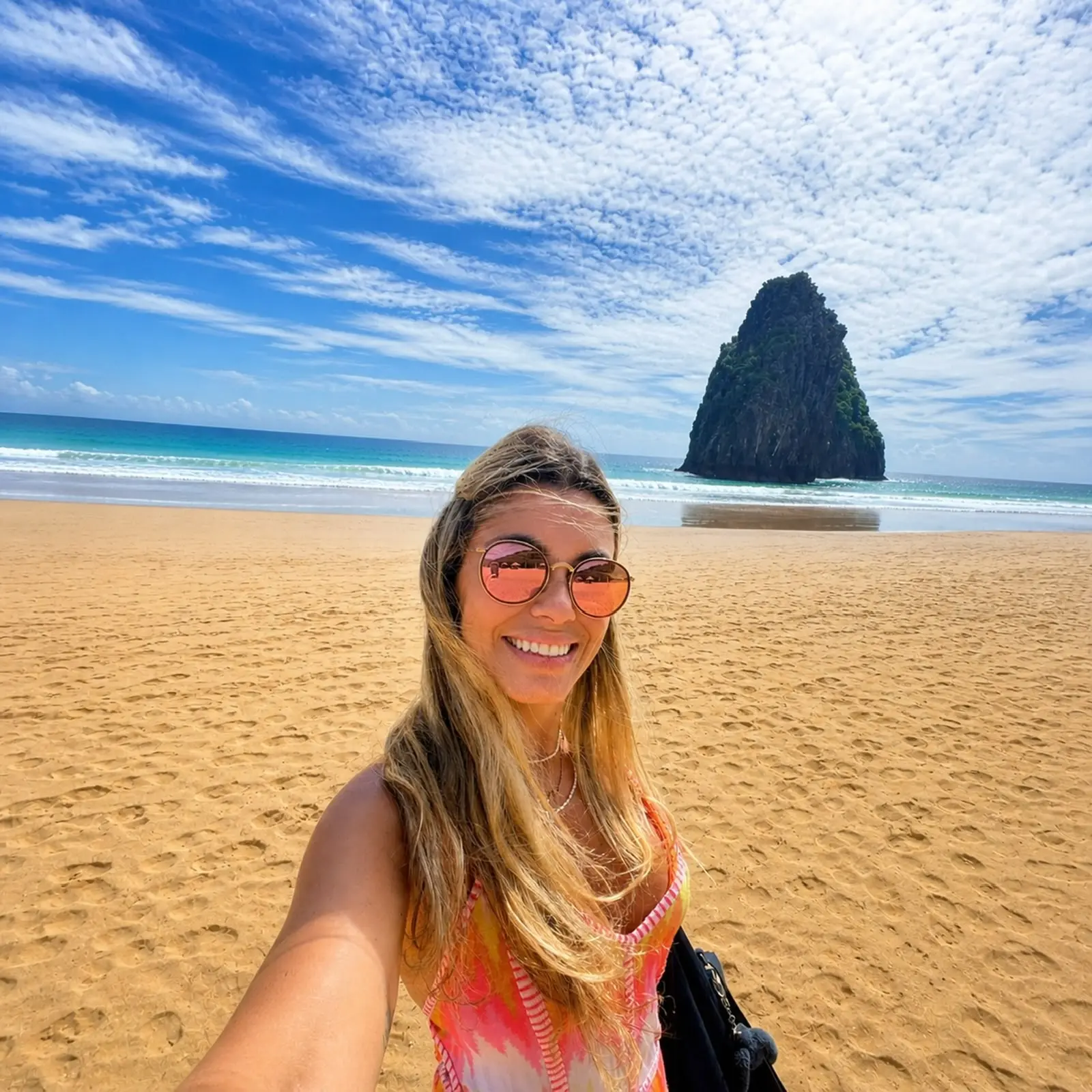 Especialista da Dicas em Noronha na praia, com o Morro do Pico ao fundo