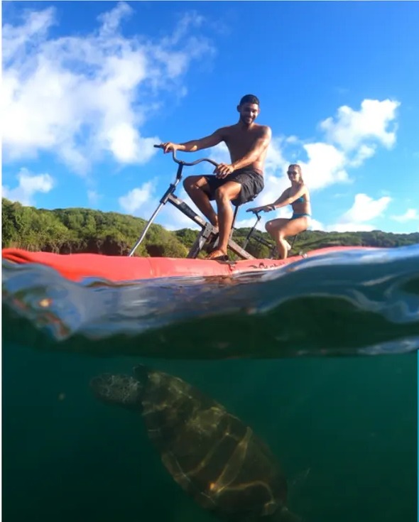Casal em bikes aquáticas com tartaruga nadando sob a água