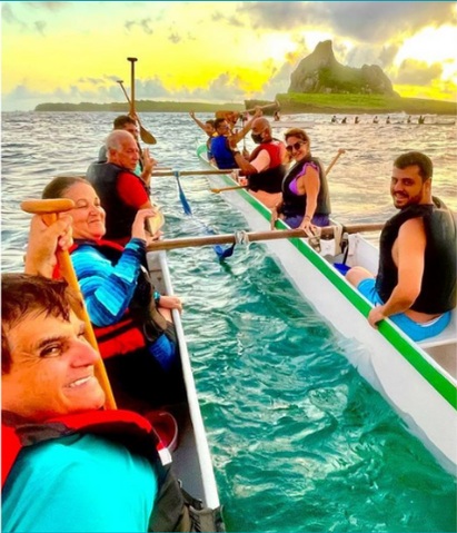 Grupo remando em canoa havaiana durante o pôr do sol em Fernando de Noronha